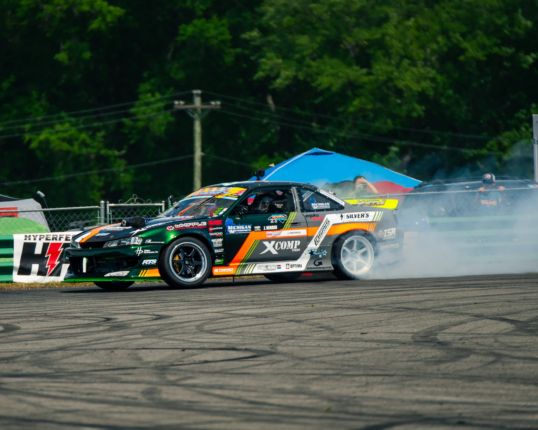 Jonathan Nerren's green, orange, and black Enjuku Racing Nissan S14 drifting through tire smoke at HyperFest