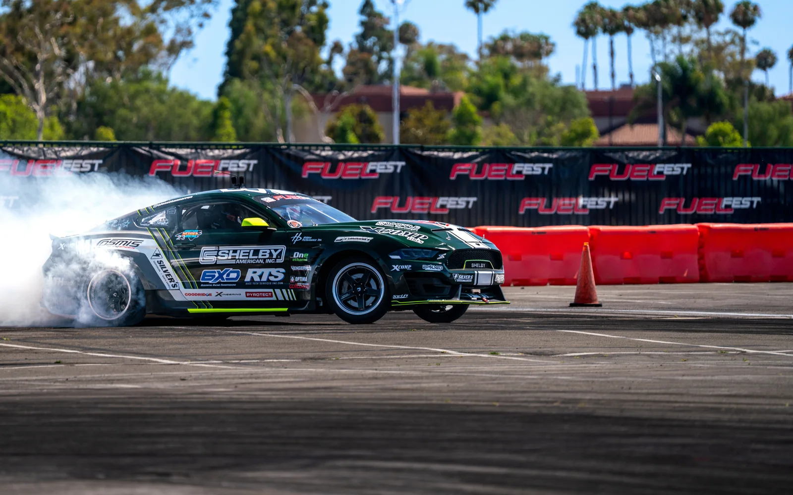 Jonathan Nerren's black, white, and green S550 Mustang performing a burnout at FuelFest